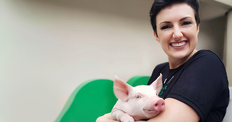 Dr. Ines Andretta looking at camera holding piglet